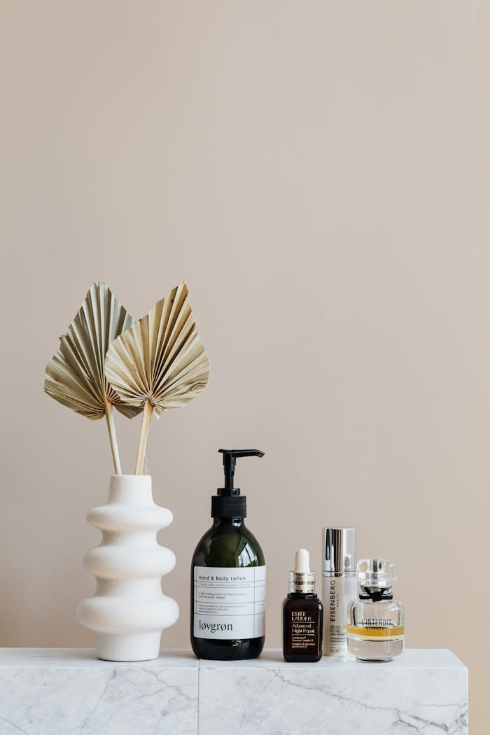 About Minimalist bathroom shelf featuring skincare bottles and decorative beige vase.